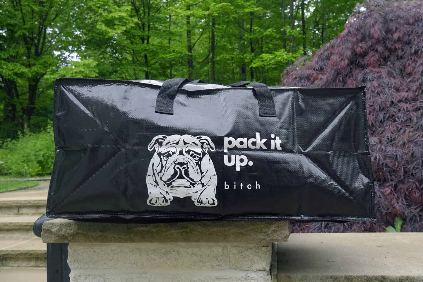 black rectangular bag with "pack it up bruh" and a black and white bulldog logo on the side.