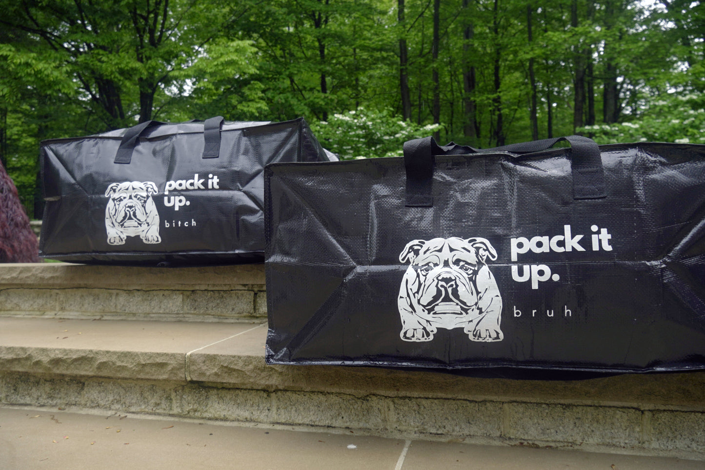 two black rectangular bags with text "pack it up bruh" and "pack it up bitch" and black and white bulldog logo on the side.